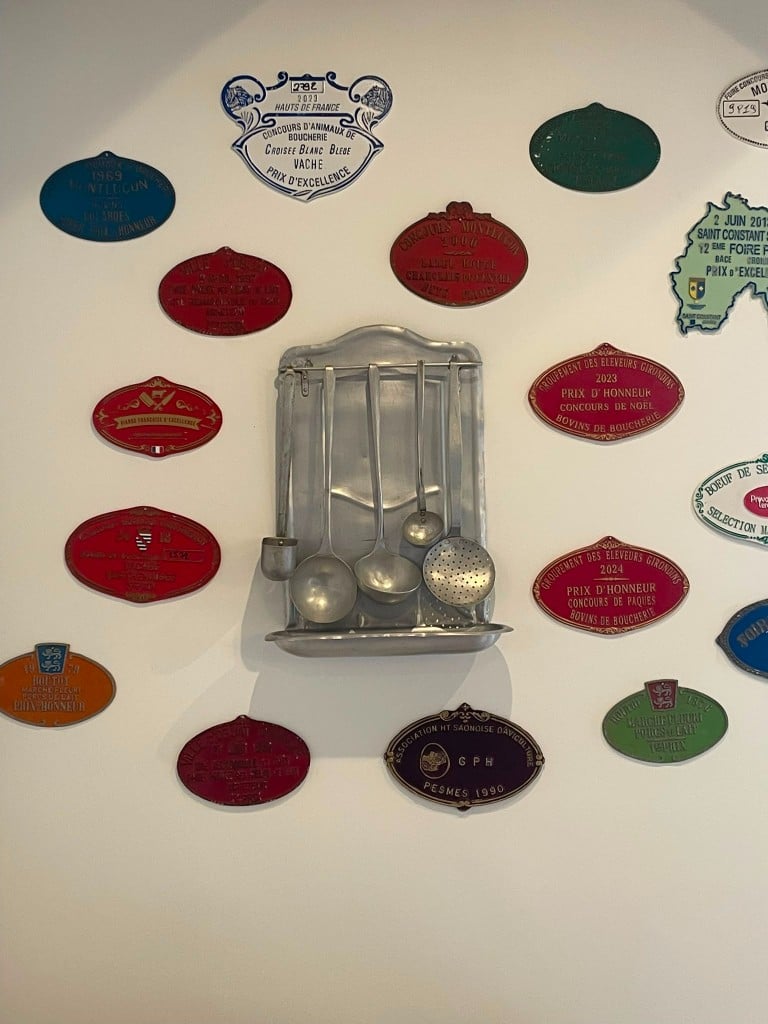 Médailles et ustensiles de cuisine accrochés au mur blanc.